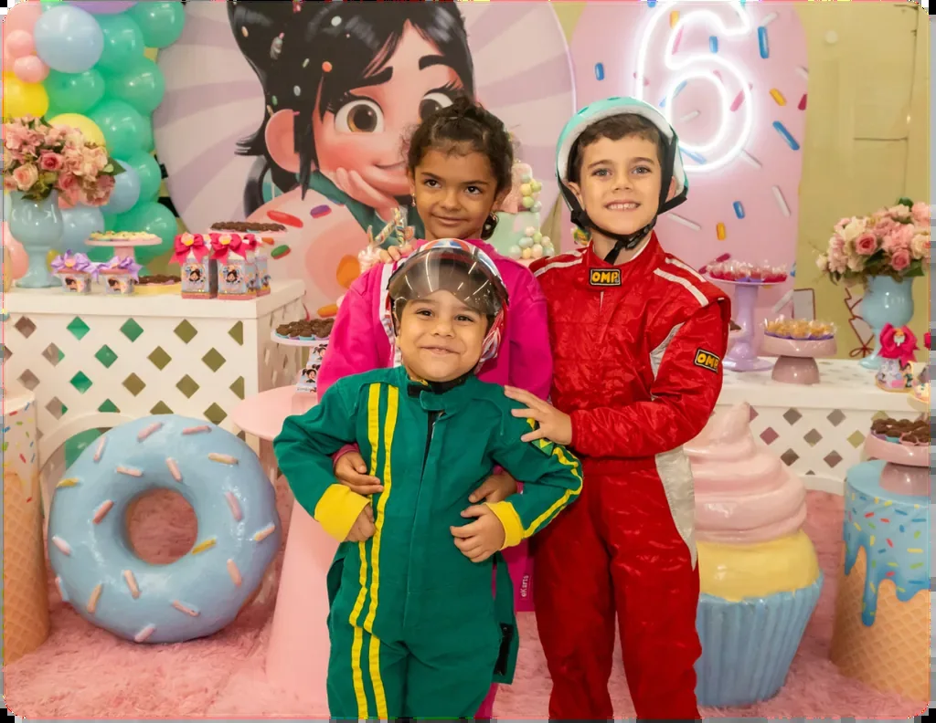 Crianças de macacão de piloto na área de festa do eKarts com decoração temática caprichada