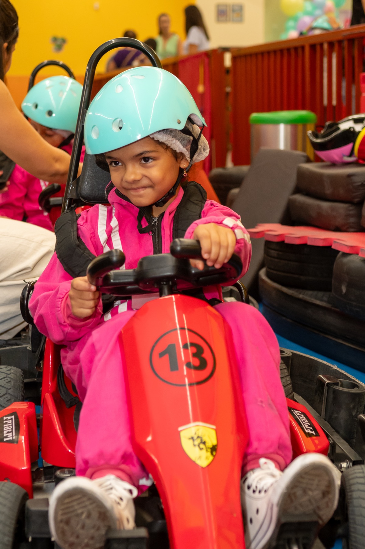 Menina sorrindo segurando balões em uma festa no eKarts