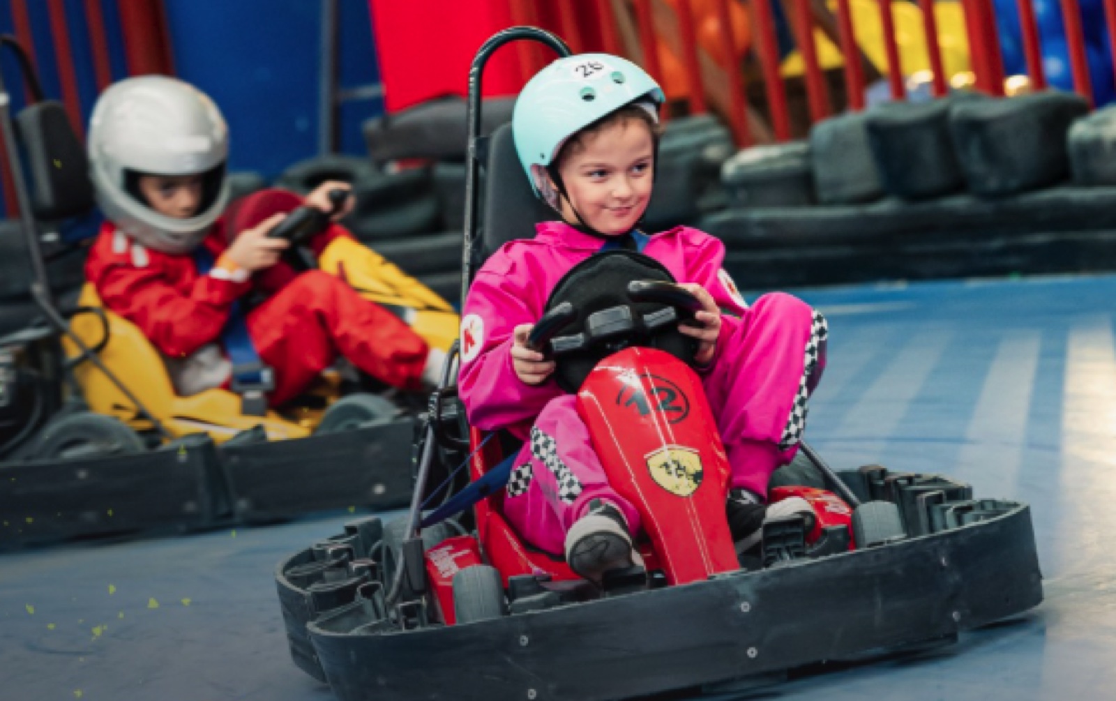 Menina de capacete pilotando o kart elétrico na pista