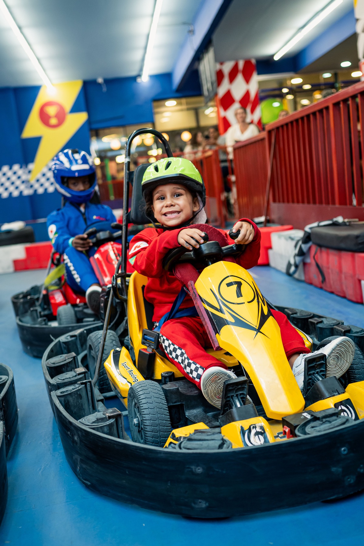 Menino sorrindo de orelha a orelha enquanto pilota o kart elétrico na pista