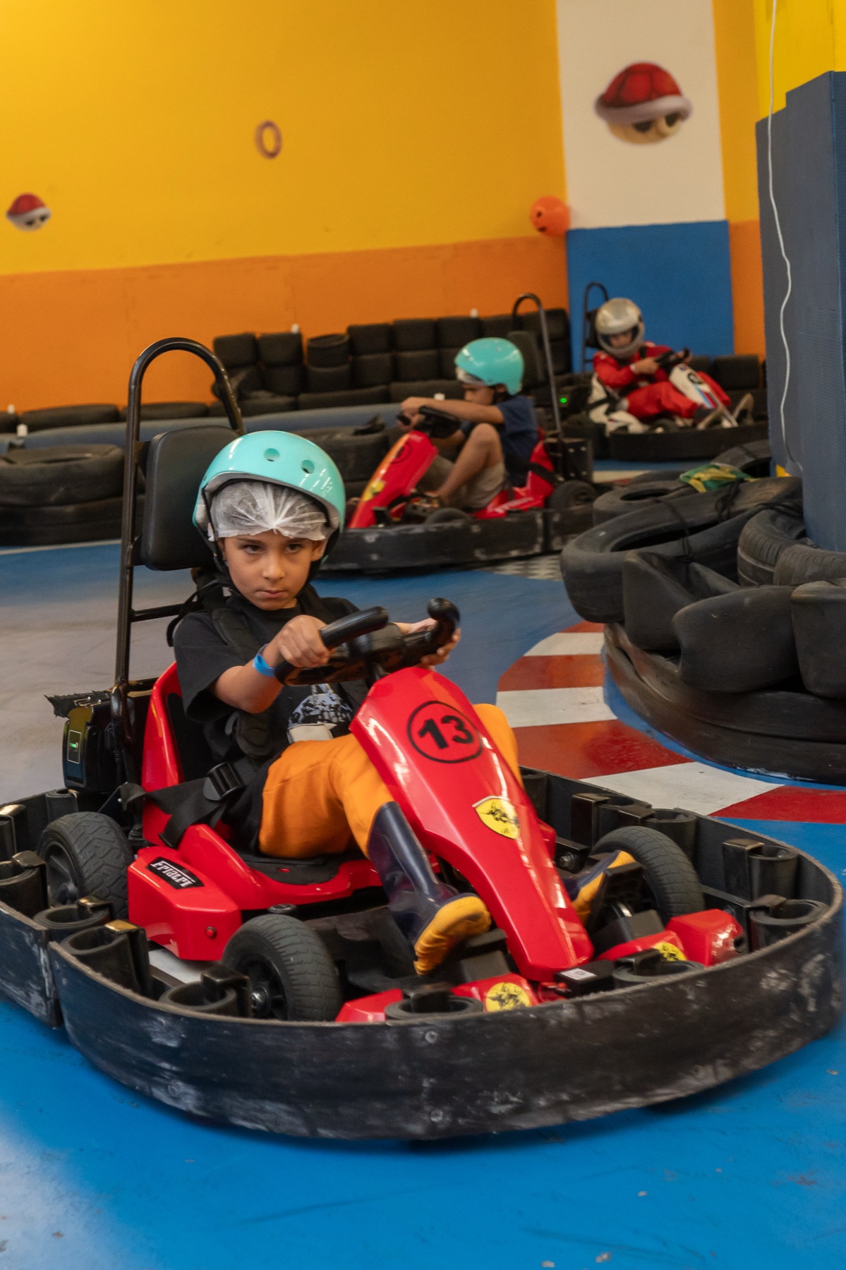 Menino concentrado ao volante do kart elétrico, expressão de piloto profissional